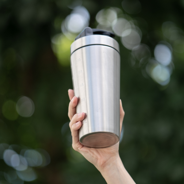holding a silver stainless steel tumbler