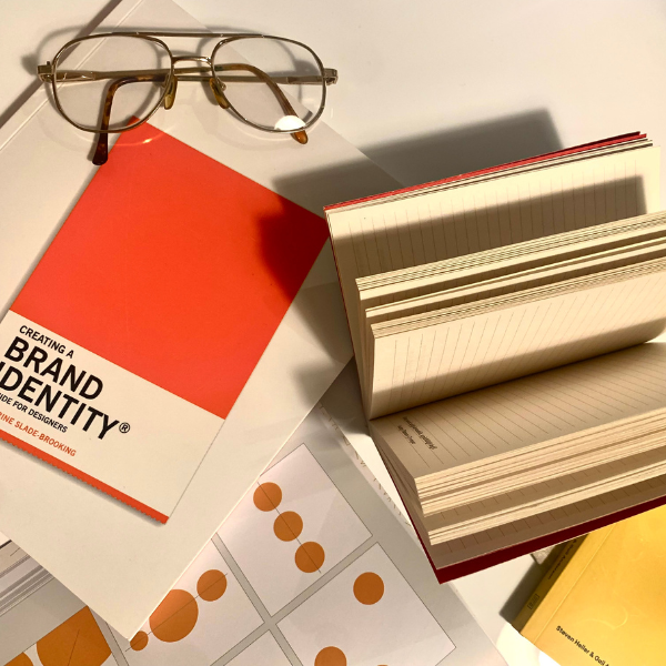 book on creating a brand identity, pair of glasses and a notebook