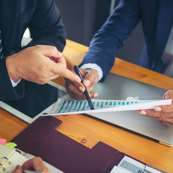 a person pointing to a document with their pen while another one takes note